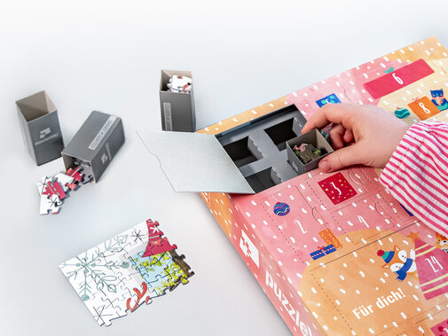 Fotopuzzle-Collage mit 24 Bildern und weihnachtlicher Schachtel